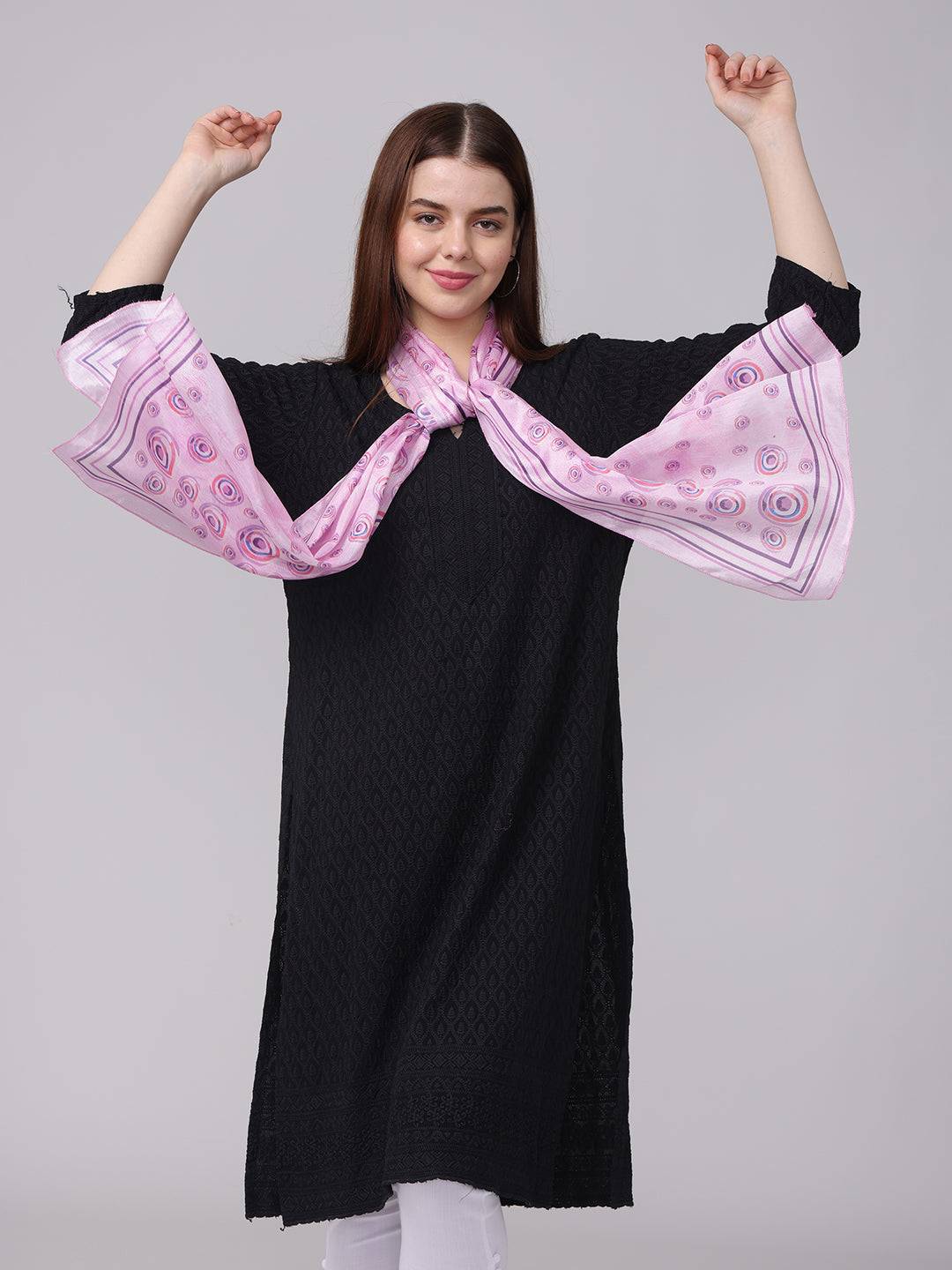 Model posing with vibrant circular printed scarf, arms raised.