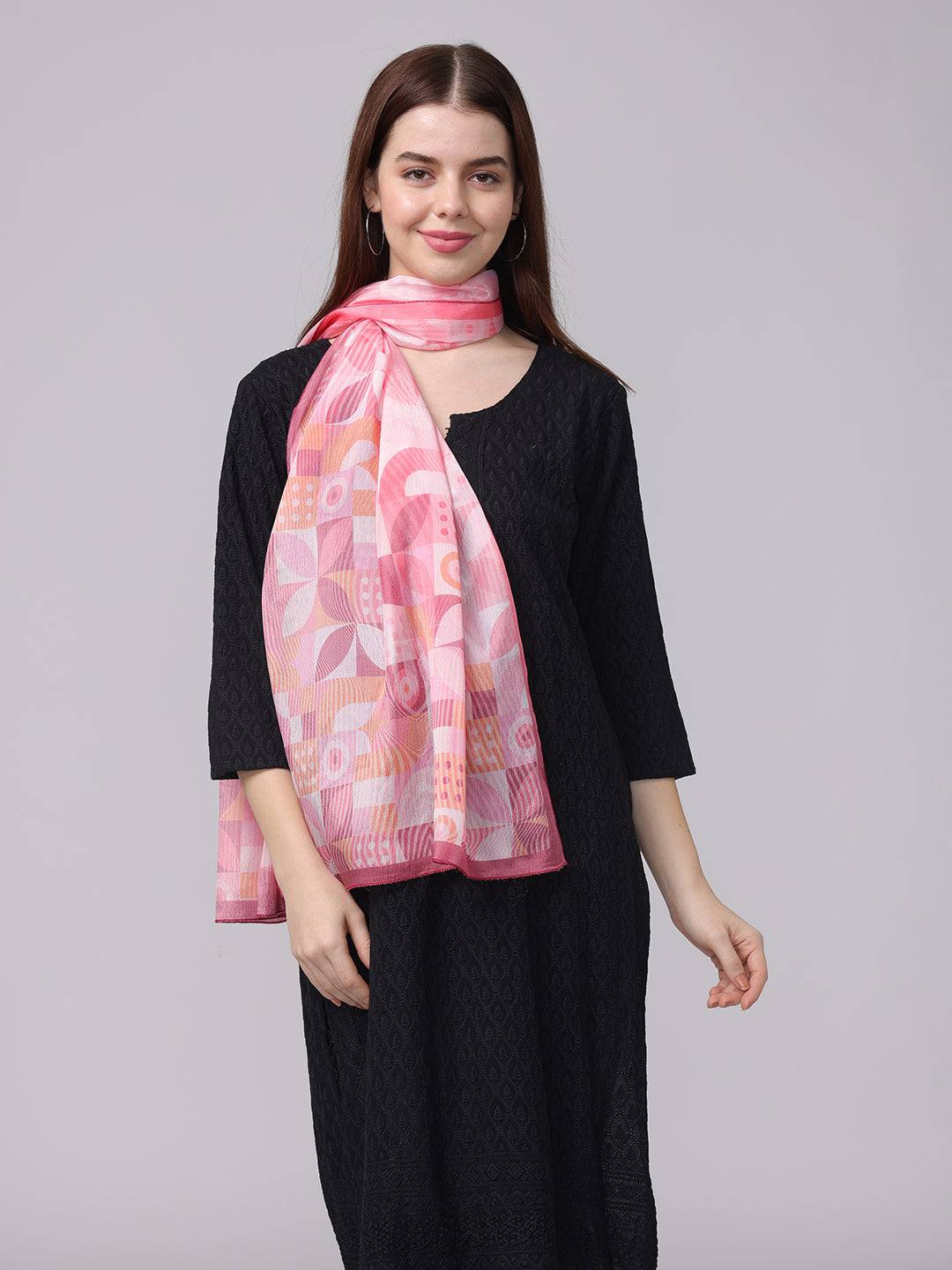 Versatile pink geometric scarf draped over black dress.