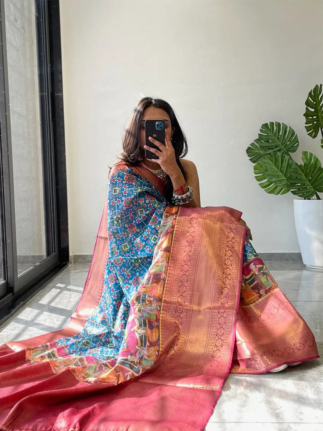 Model holding a vibrant Patola printed saree in natural light