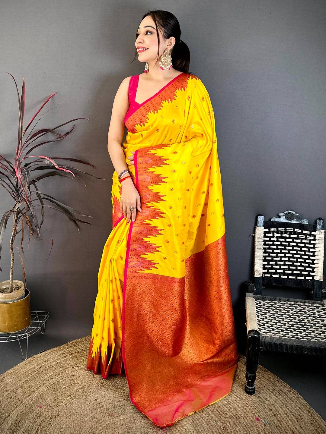 Model wearing yellow silk saree with pink border and traditional jewelry