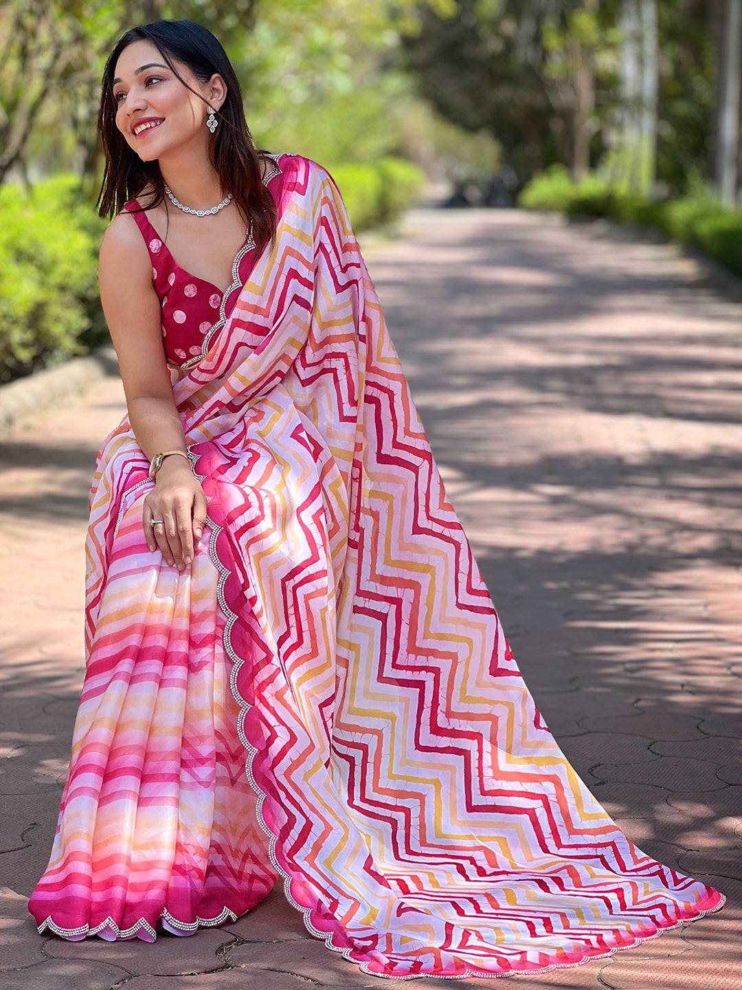 Model sitting in Leheriya striped saree, outdoor background