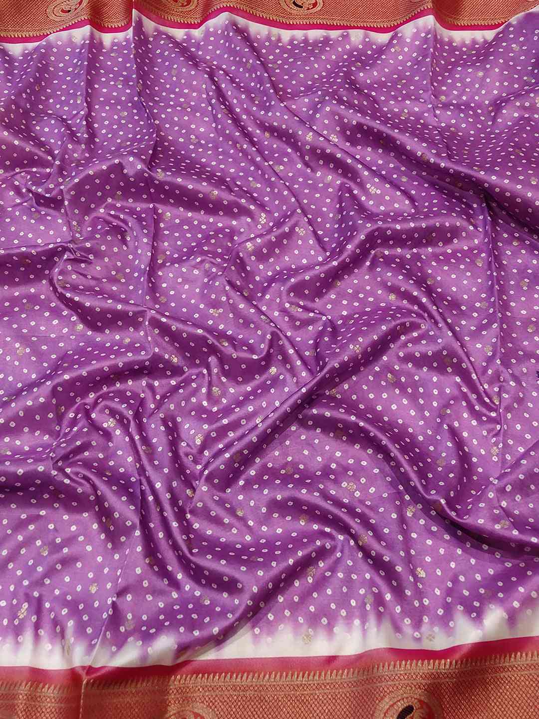 Close-up of pink Bandhani saree fabric with Paithani border