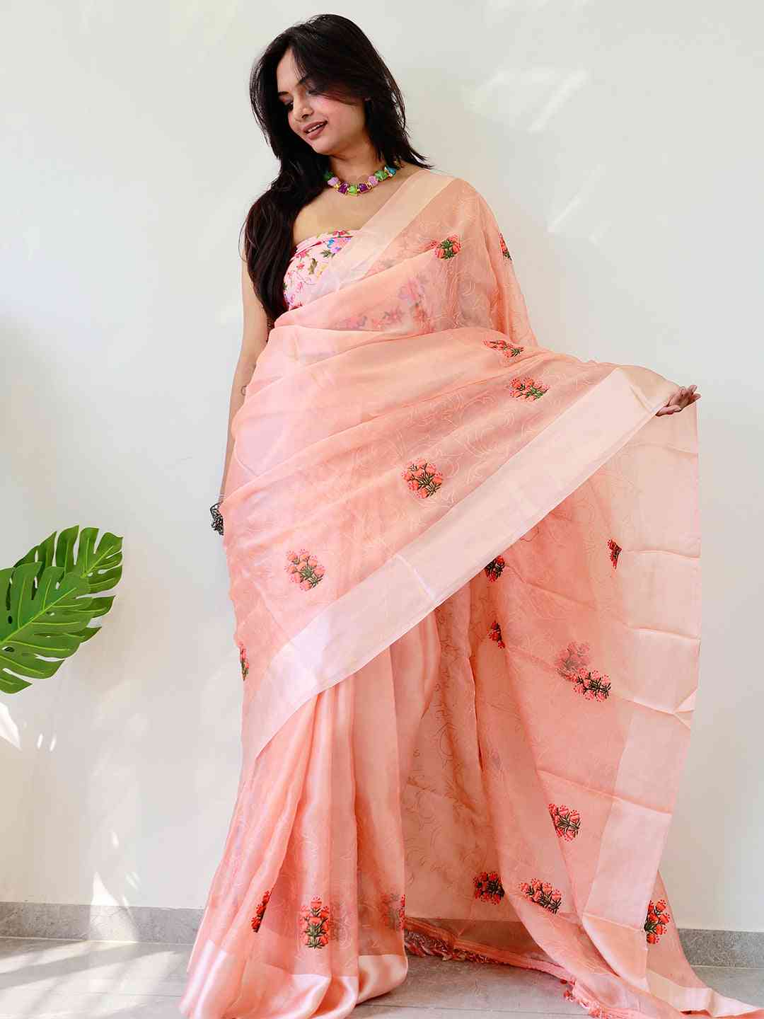 Soft chiffon satin saree with floral embroidery, draped elegantly.