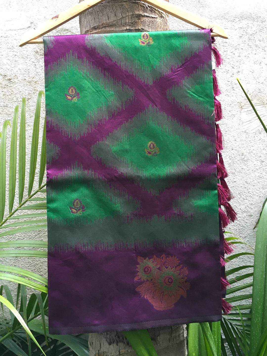 Dark green tussar silk Ikkat weaving saree on hanger.