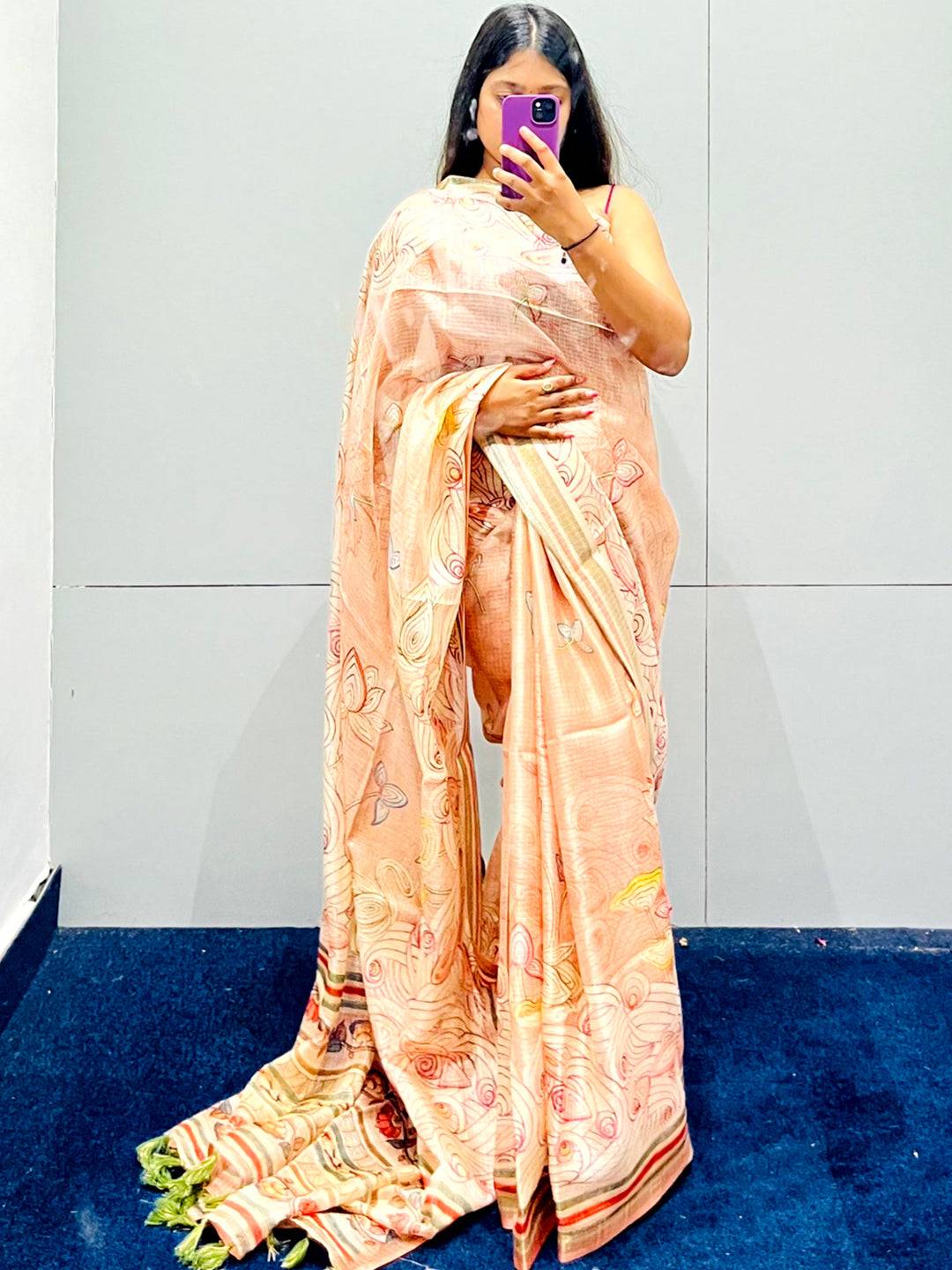 Peach silk saree with intricate floral Kalamkari print, displayed gracefully.