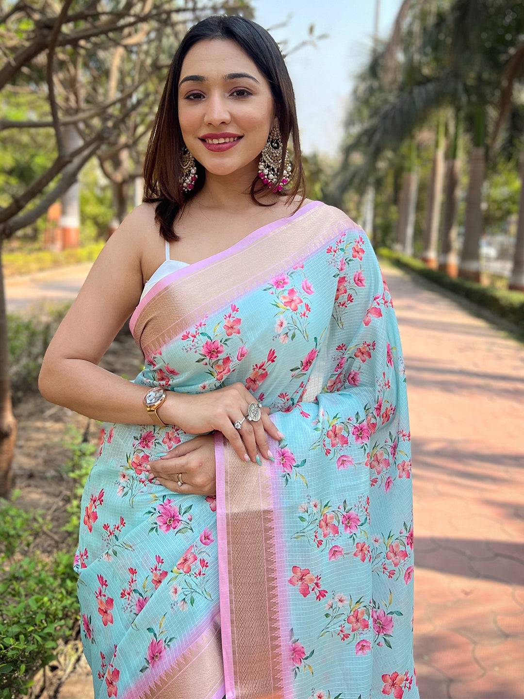 Smiling woman in Aqua Kota saree with floral print and pink accents