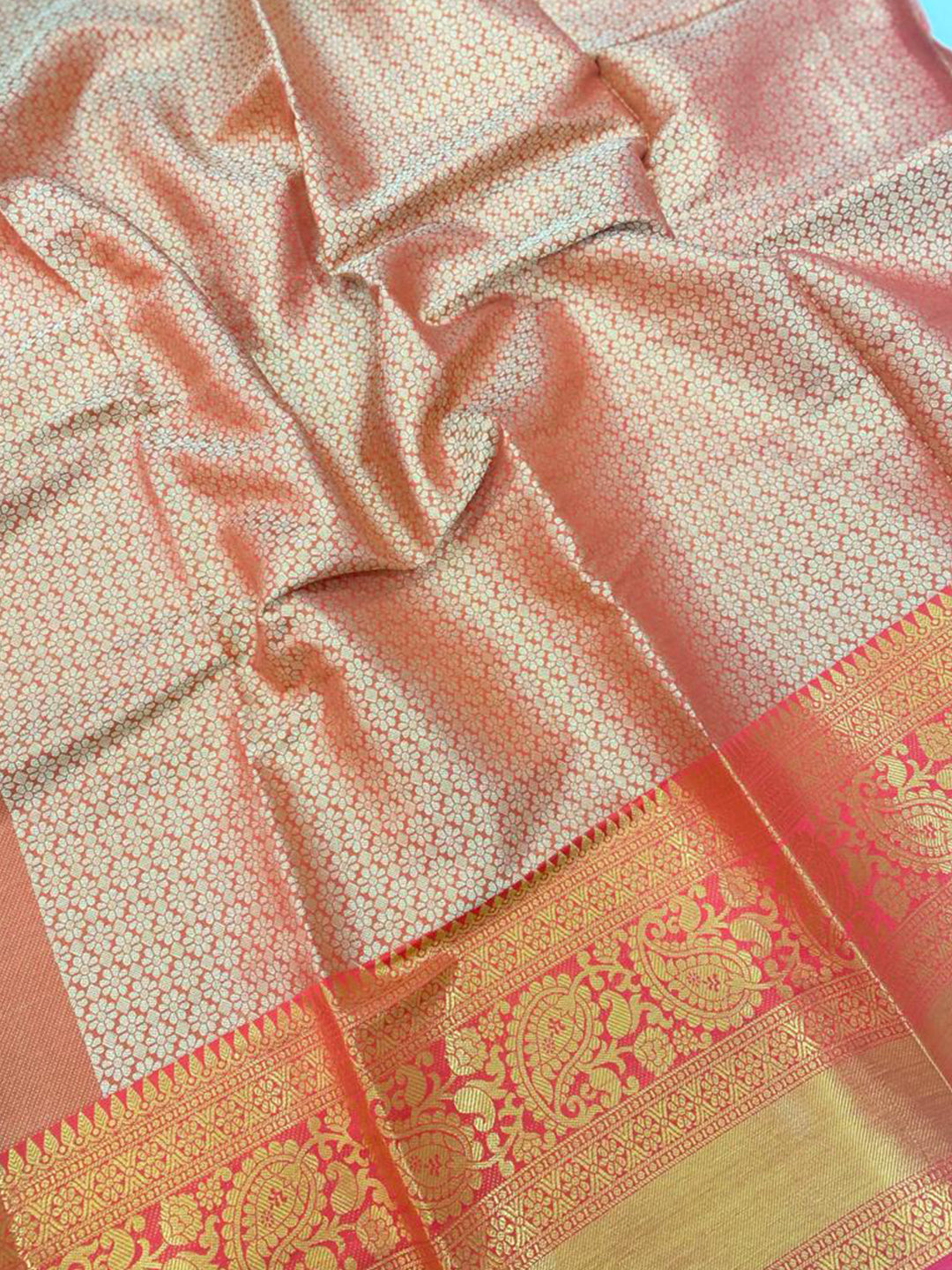 Close-up of gold zari Kanjivaaram silk saree fabric with detailed motifs.