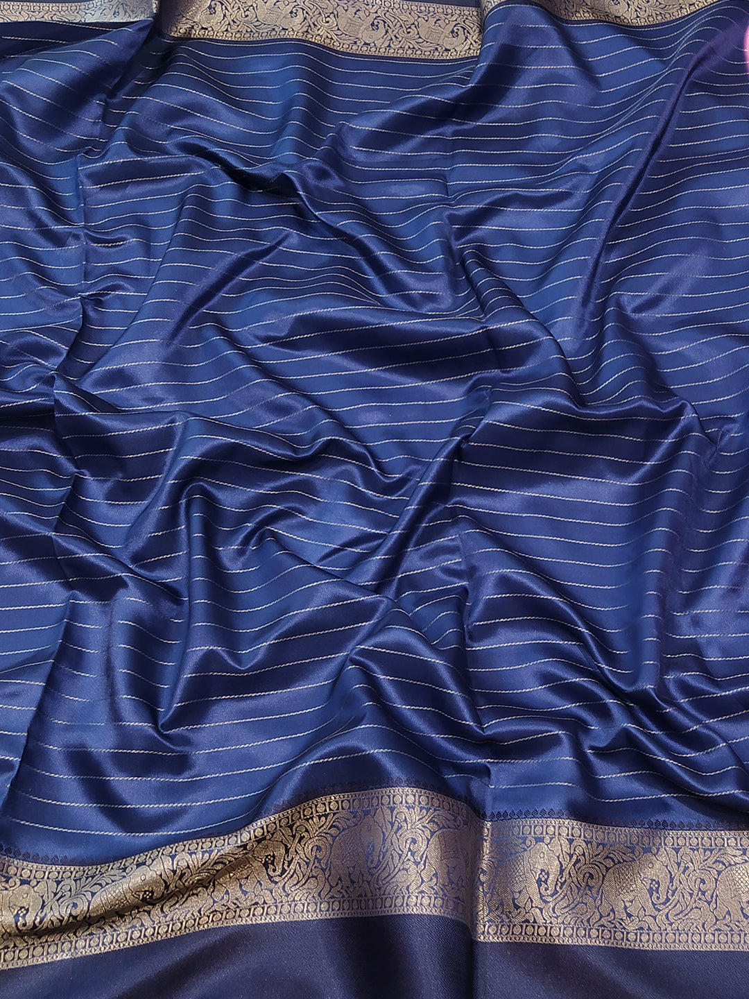 Close-up of blue silk saree fabric with gold zari stripes
