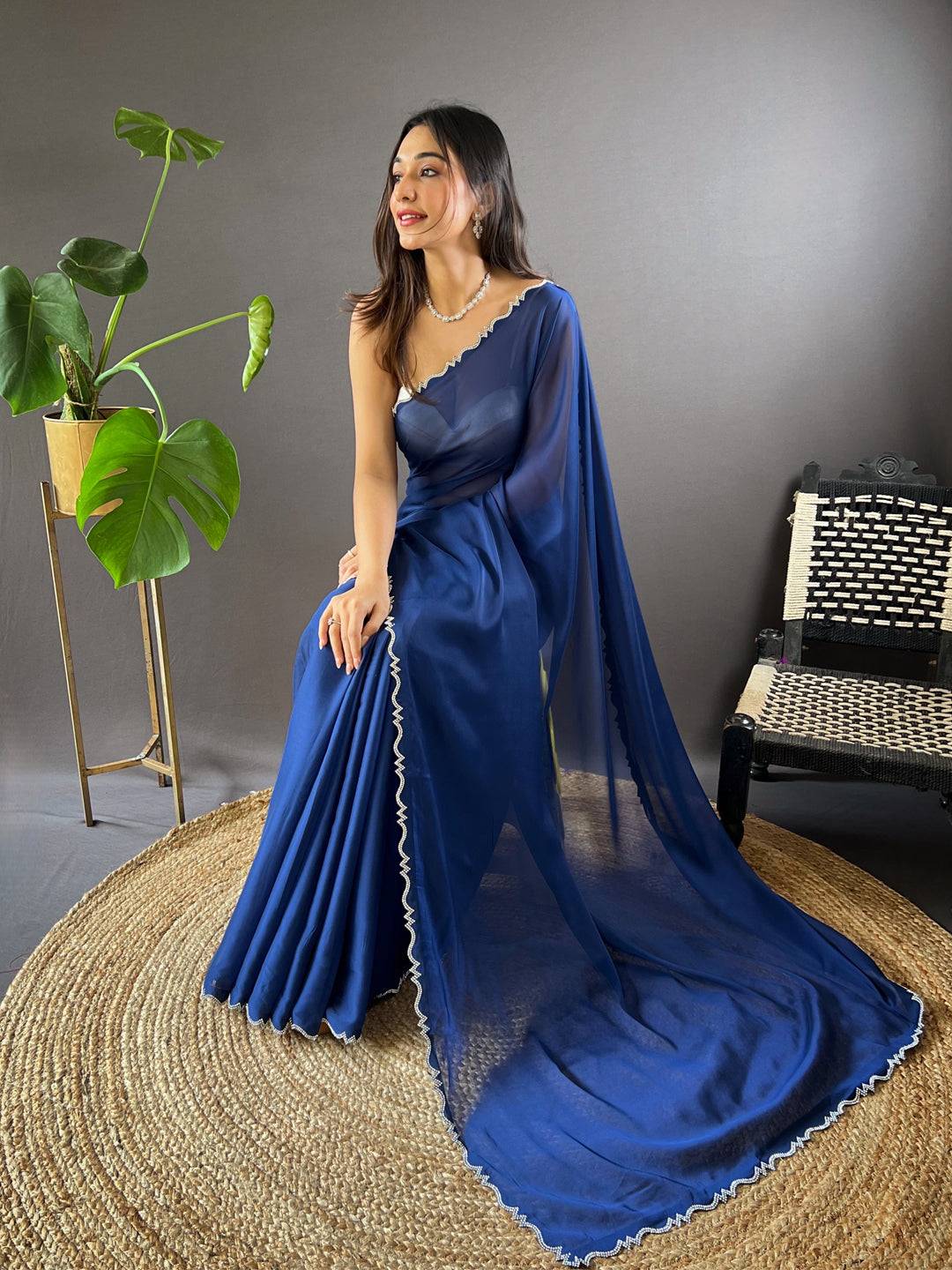 Model seated in blue Rangoli silk saree with detailed border