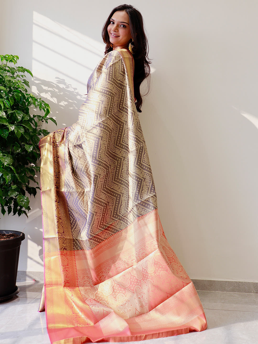 Model showcasing gold zari Kanjivaaram silk saree with intricate patterns.