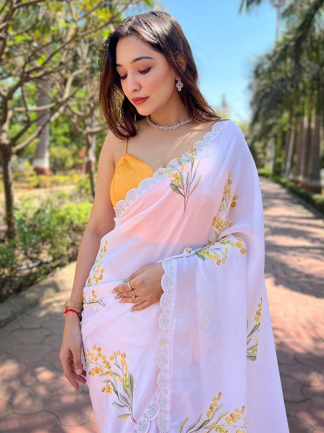 Woman in white floral satin georgette saree with zircon border