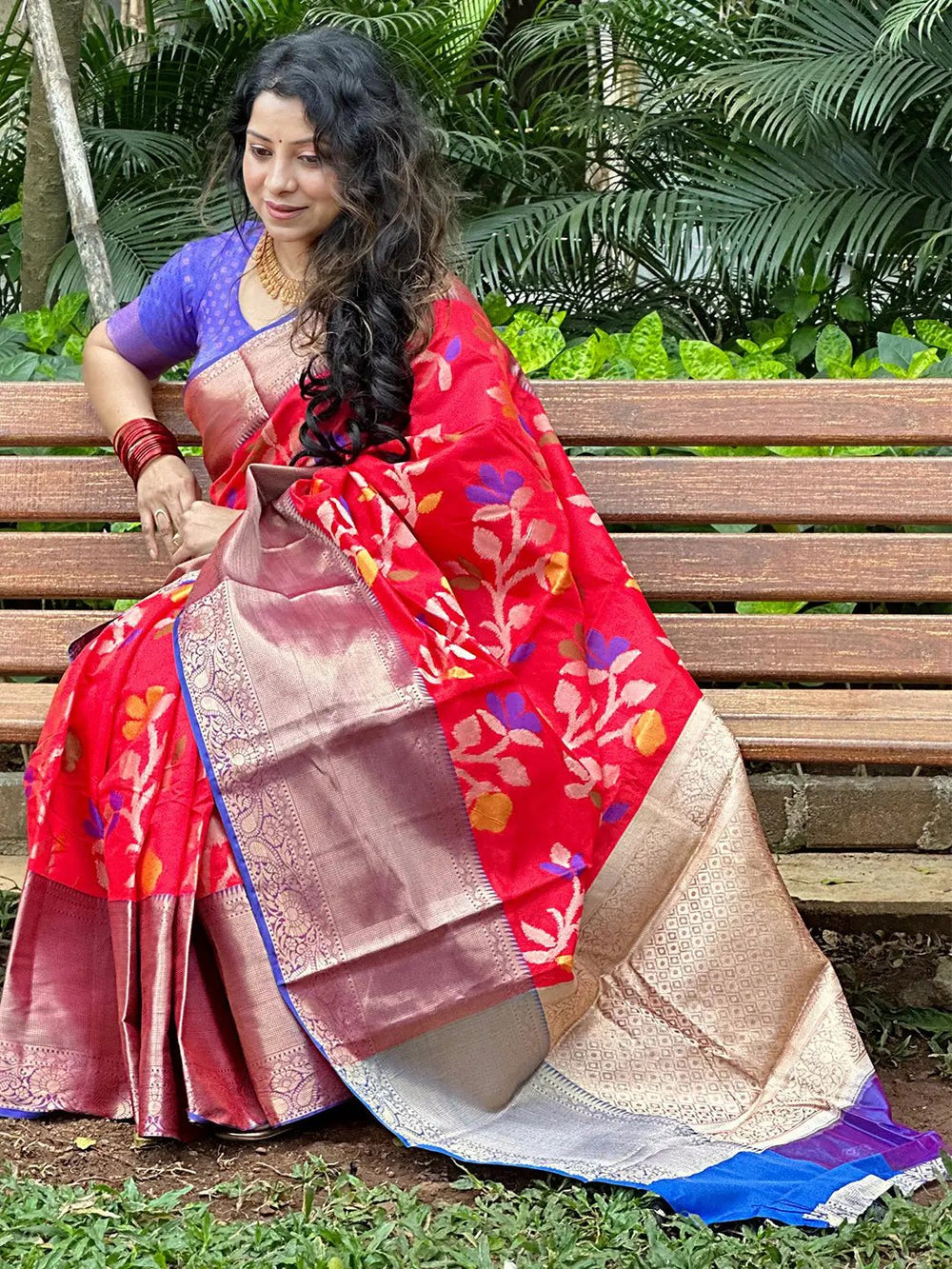 Woman seated in red Banarasi saree with Minakari Ikkat