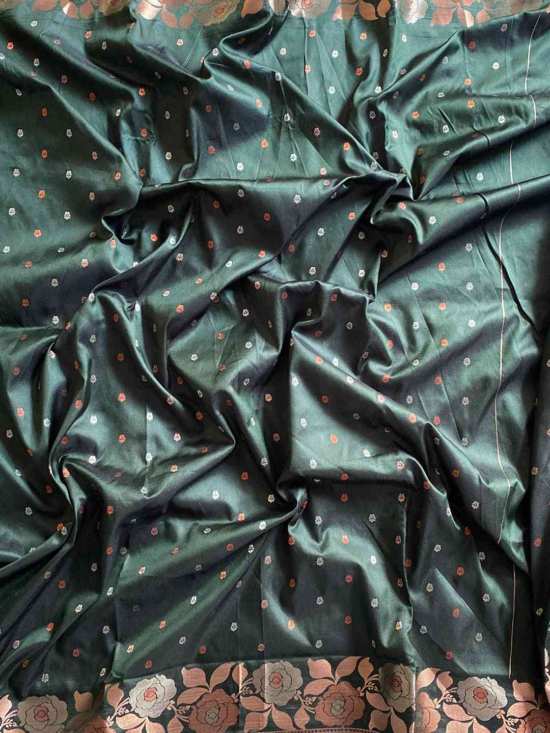 Close-up of bottle green Banarasi silk saree fabric with zari