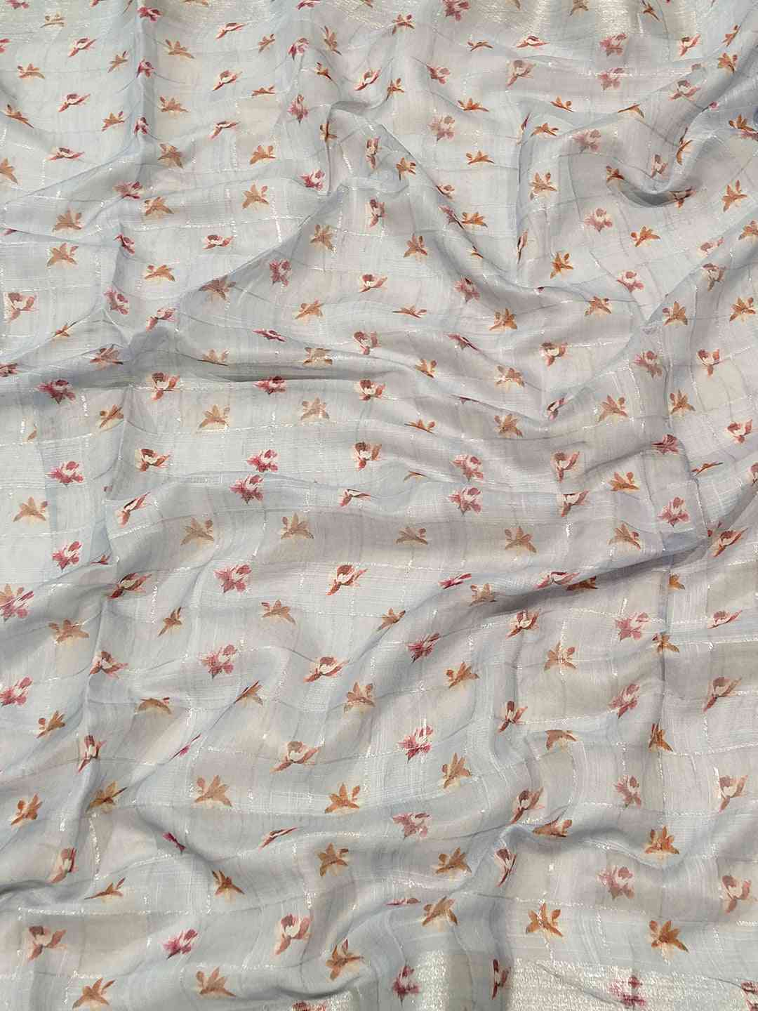 Close-up of blue saree fabric with floral and zari chex pattern.