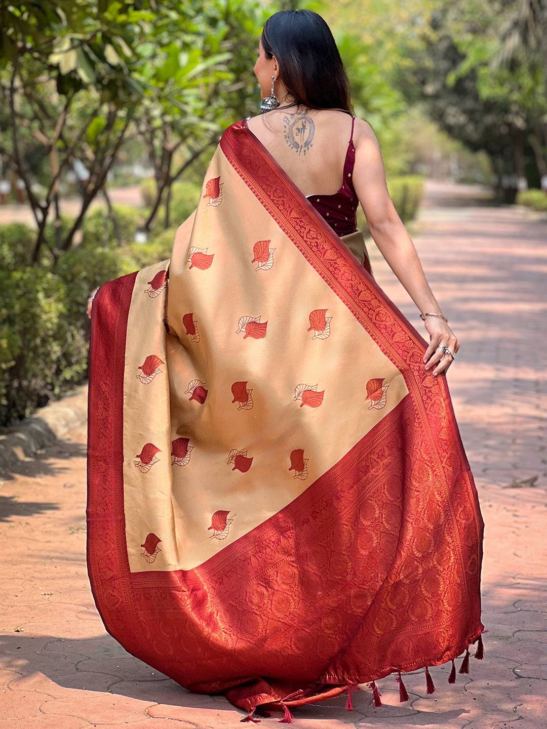 Back view of beige saree with red border and leaf patterns