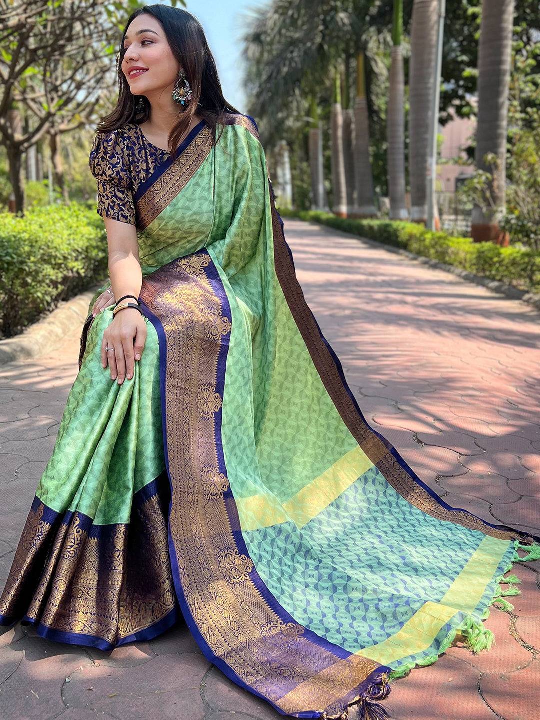 Seated woman in green Kanjivaram silk saree with detailed pallu