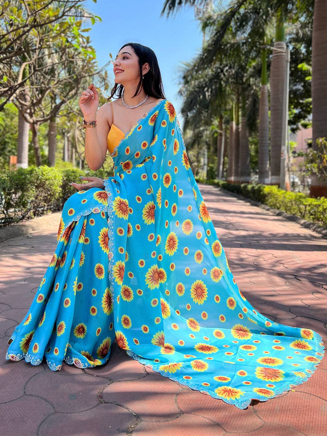 Sitting model in blue sunflower print saree with Swarovski border