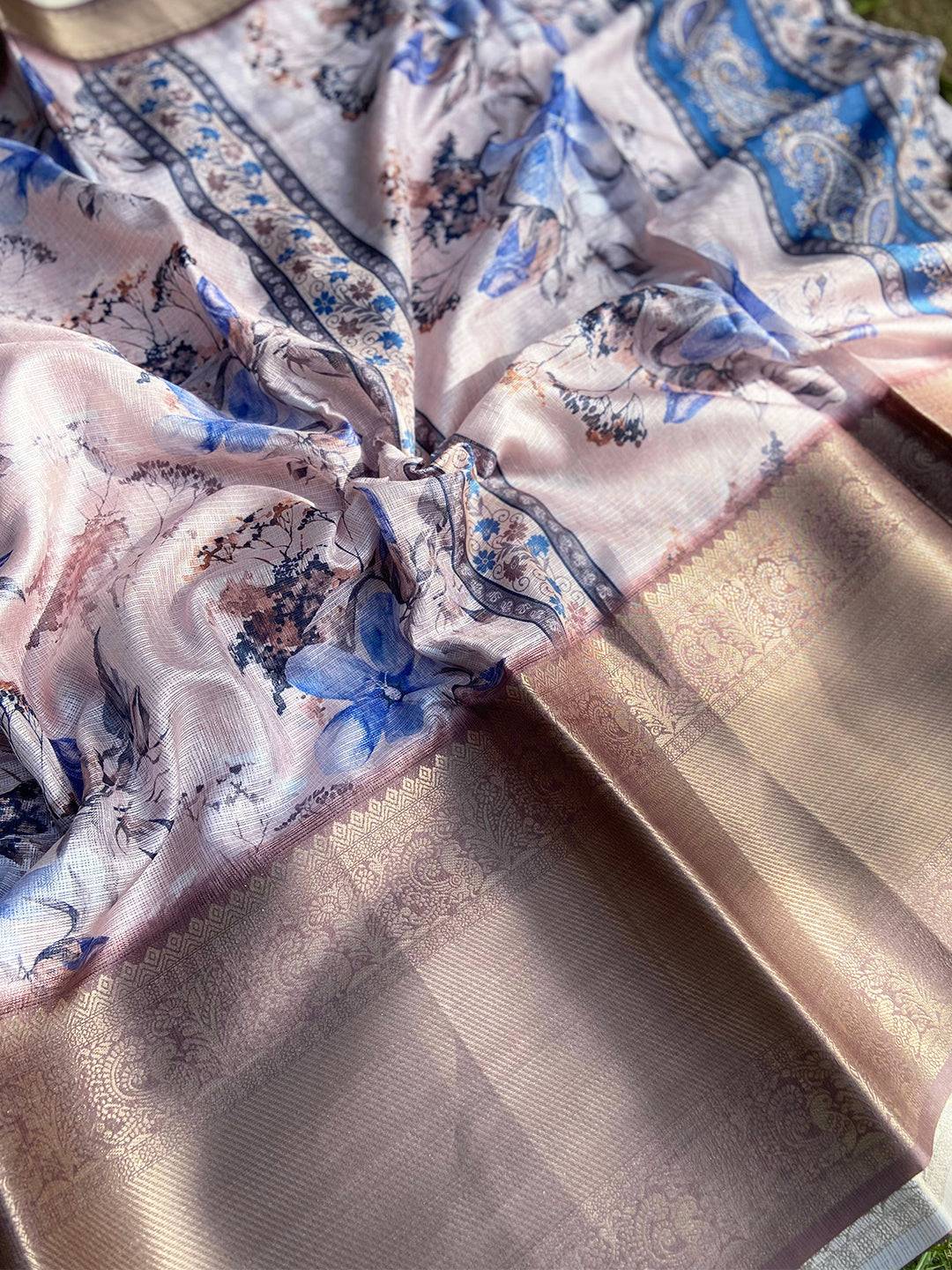 Close-up of light pink saree with intricate floral print and gold border