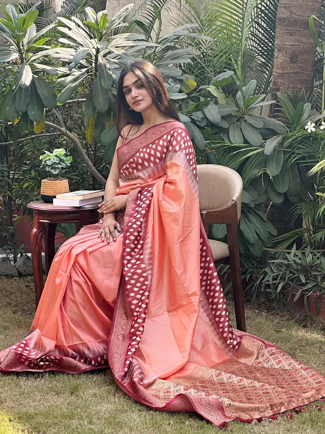 Peach Banarasi saree with Patola pallu, seated in garden