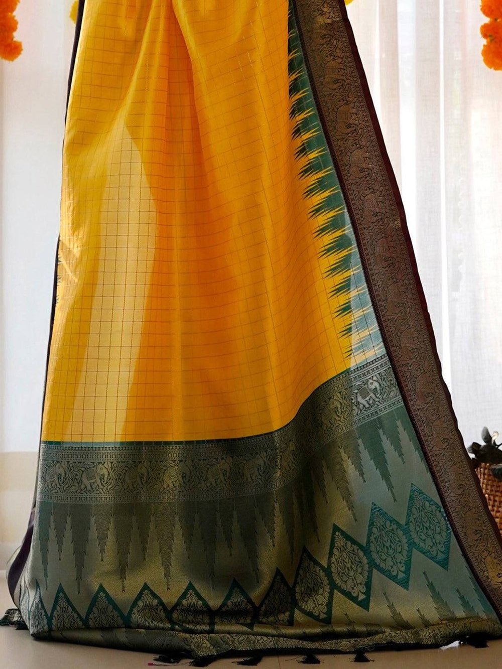 Detailed view of yellow Banarasi saree with green and black border.
