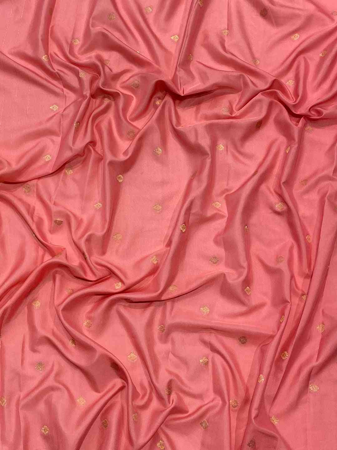 Close-up of pink ombre silk fabric with gold accents