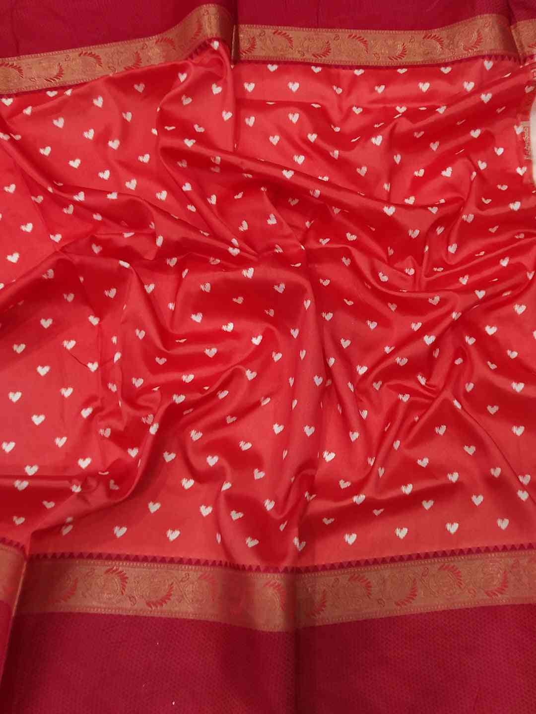 Close-up of red Gadwal border on soft silk saree with heart patterns