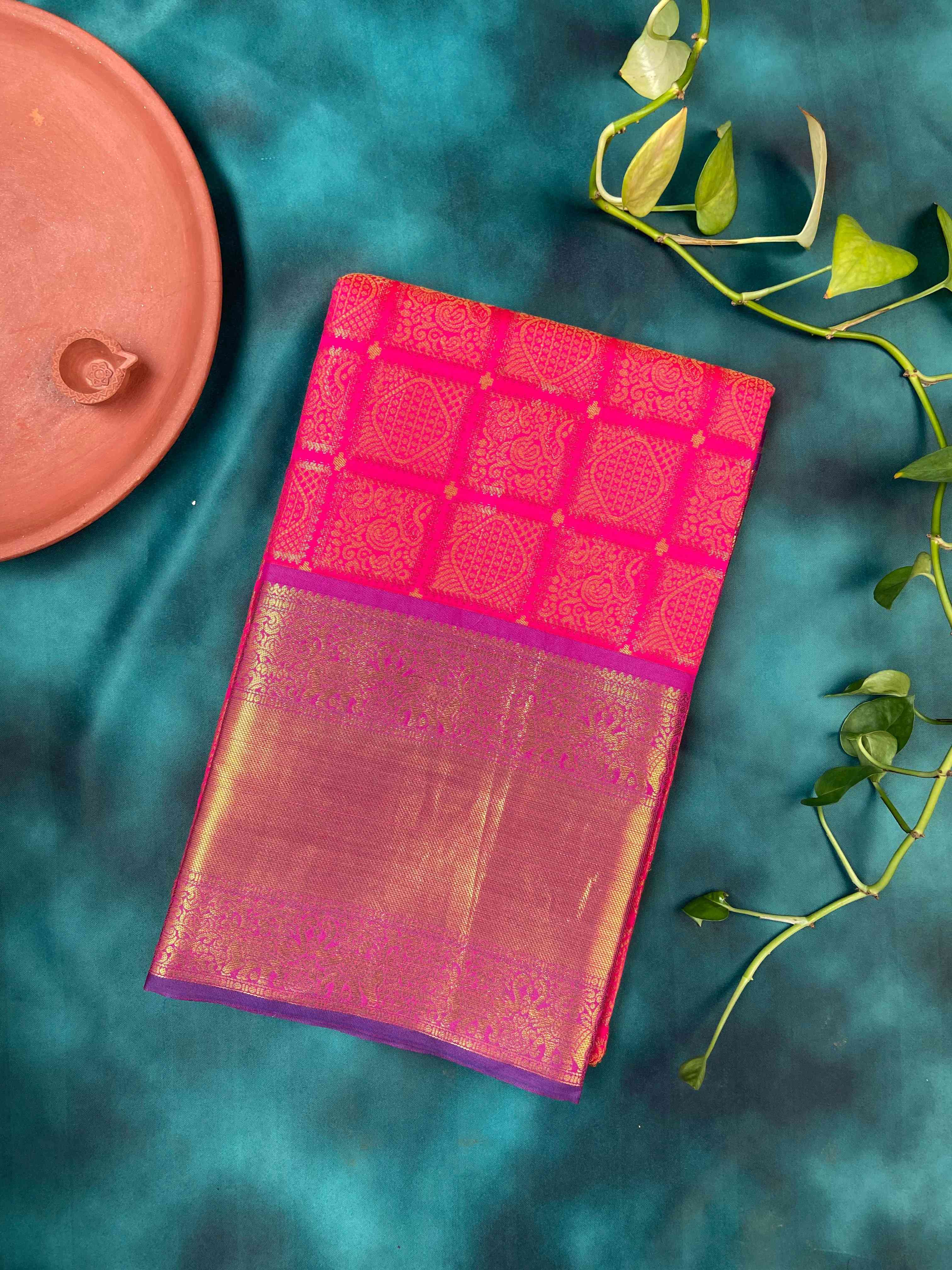 Folded pink Kanjivaram silk saree with gold zari border