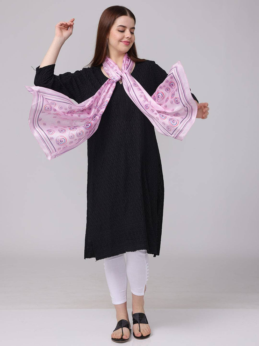 Model with vibrant circular printed scarf, arms extended.