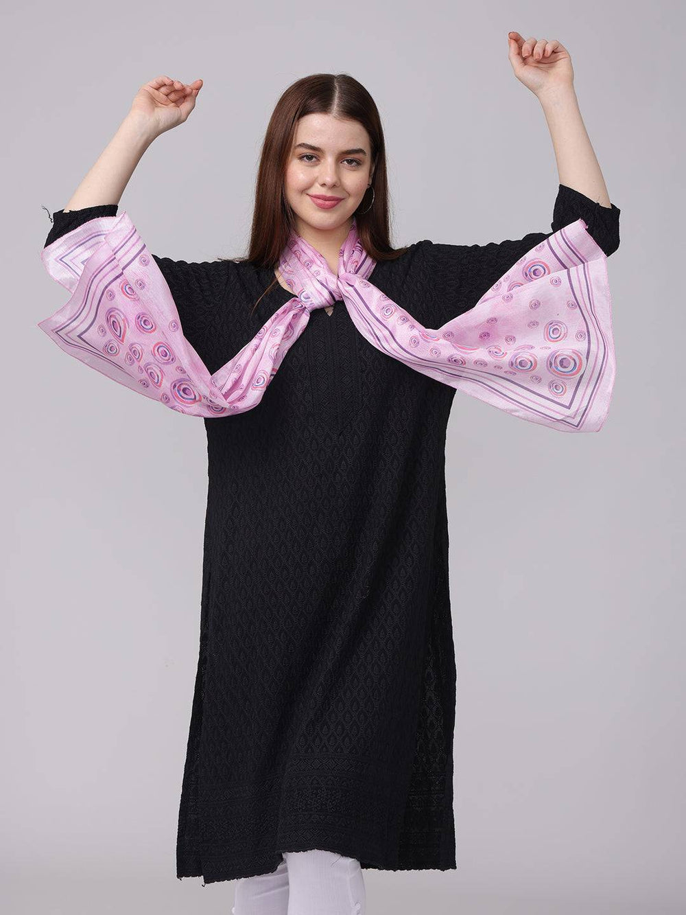 Model posing with vibrant circular printed scarf, arms raised.