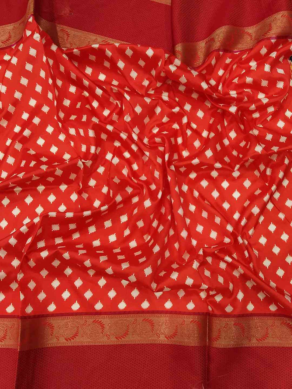 Red and gold patterned soft silk saree fabric close-up