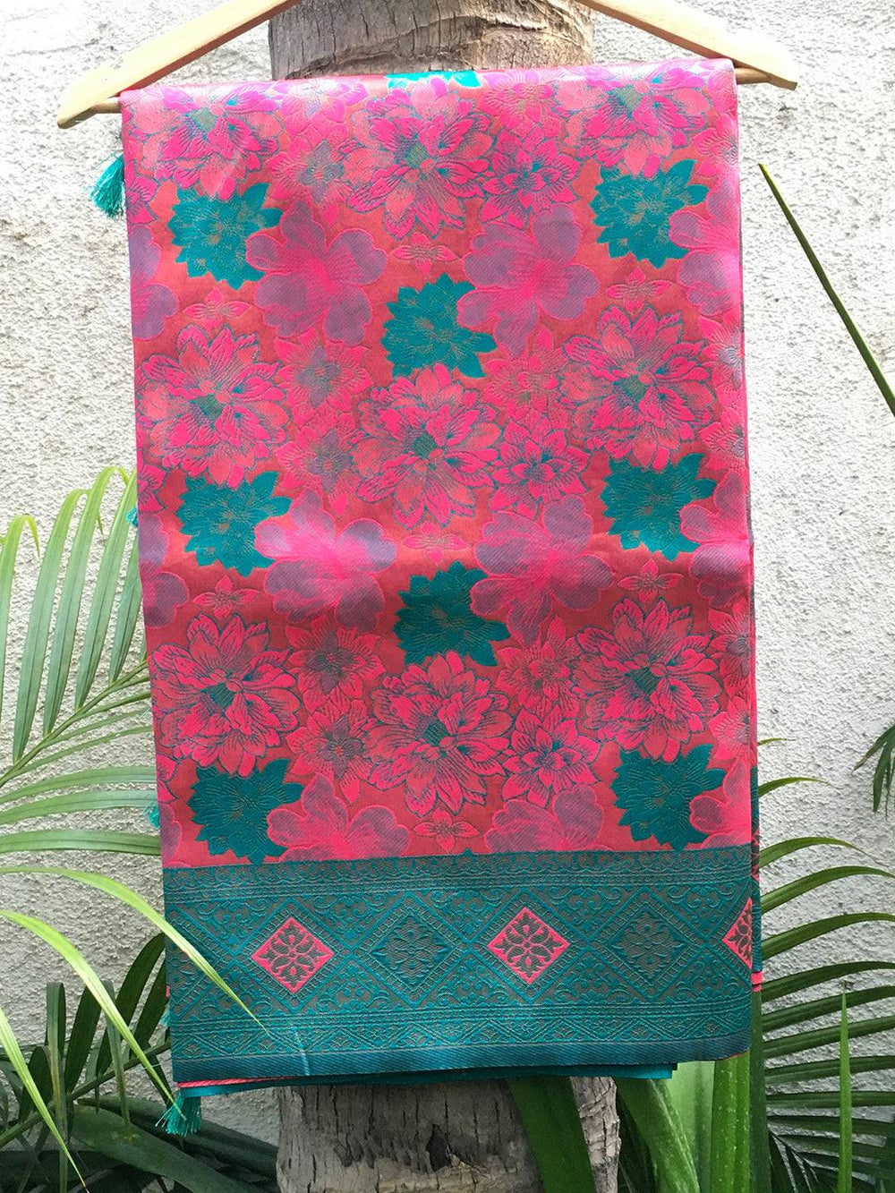 Deep pink silk saree draped on hanger showcasing design