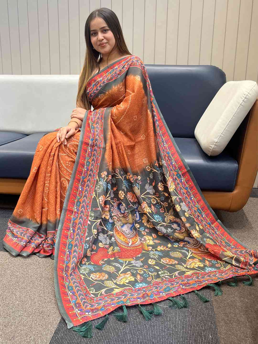 Orange linen saree with Bandhej and Kalamkari print, seated view