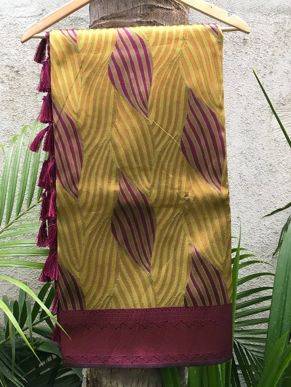 Green tussar silk ikkat saree draped on hanger with tassels