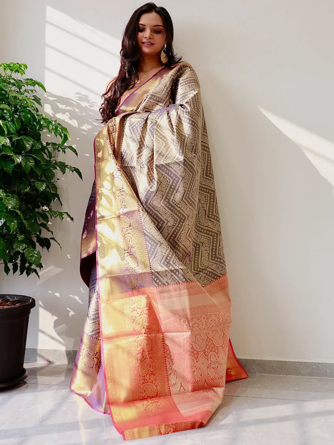 Model showcasing gold zari Kanjivaaram pattu silk saree with rich patterns.
