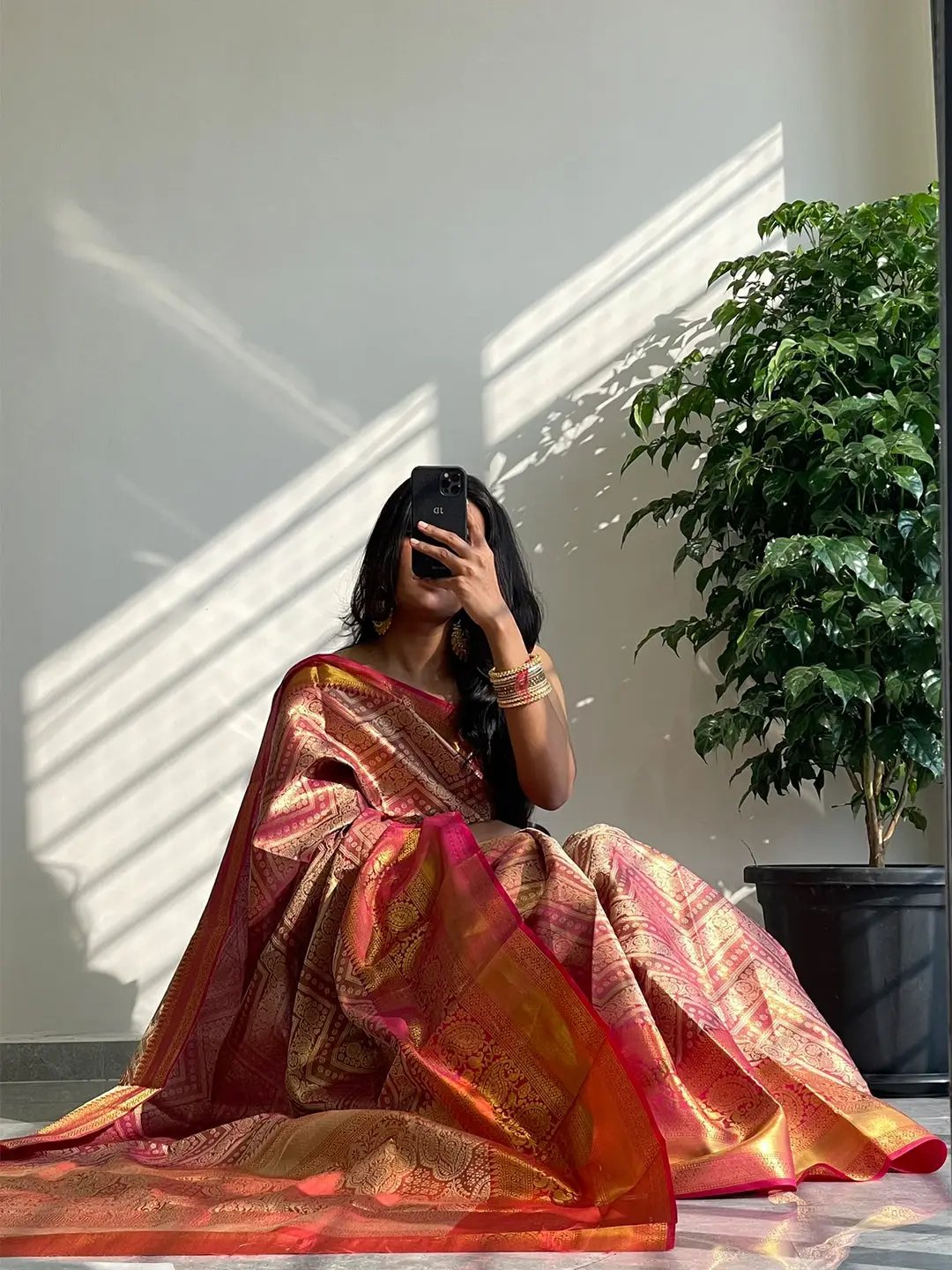 Sitting pose with gold zari Kanjivaaram pattu silk saree and phone.