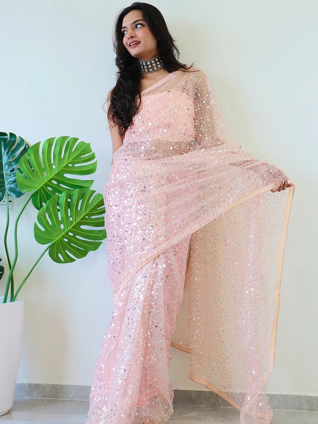 Model showcasing net saree with intricate sequins work.
