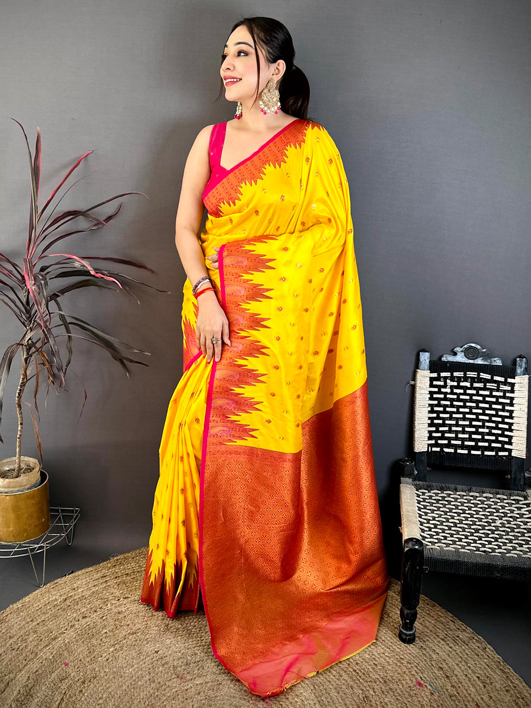 Model wearing yellow silk saree with pink border and traditional jewelry