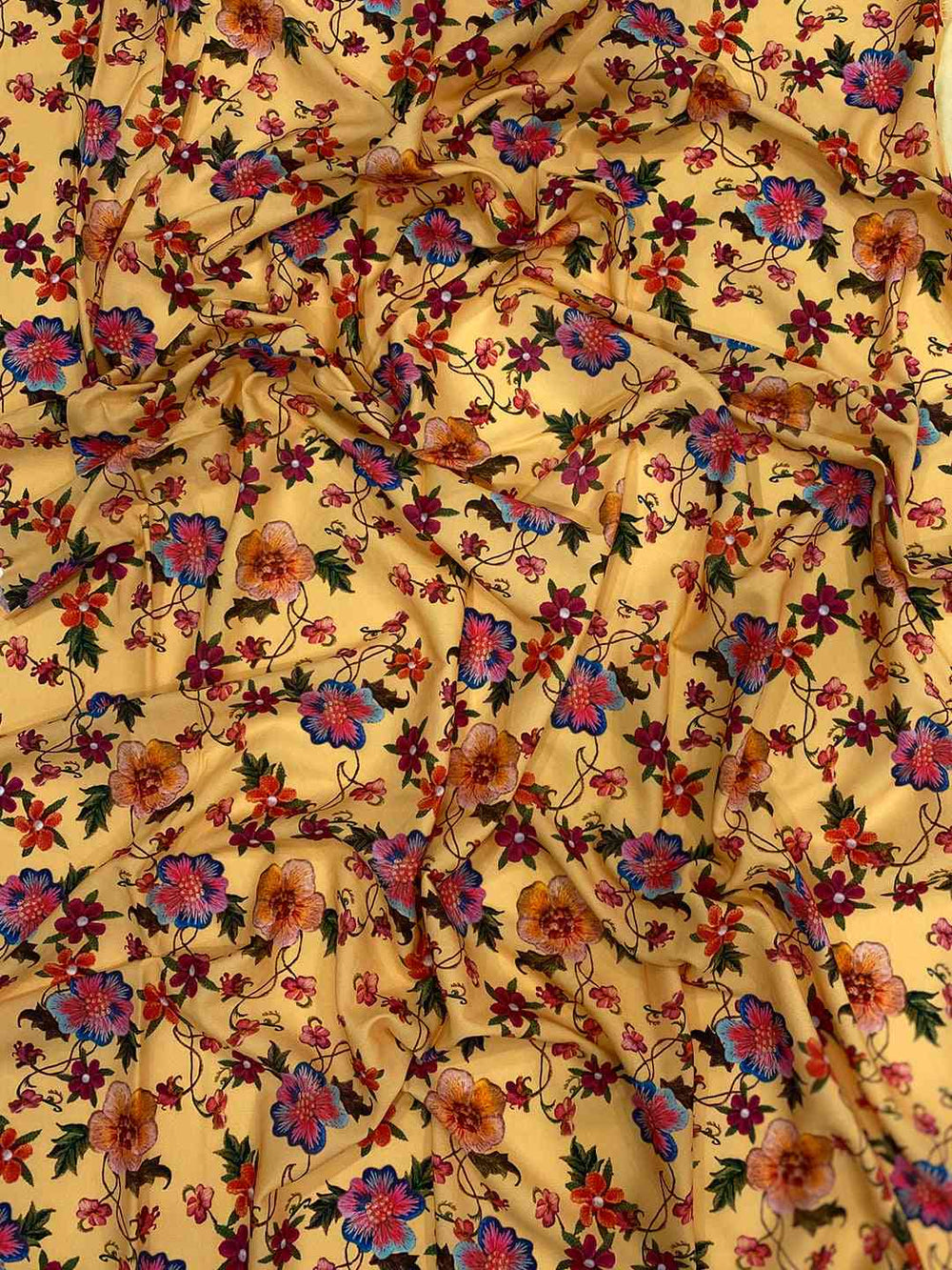 Close-up of yellow fabric with intricate floral embroidery.