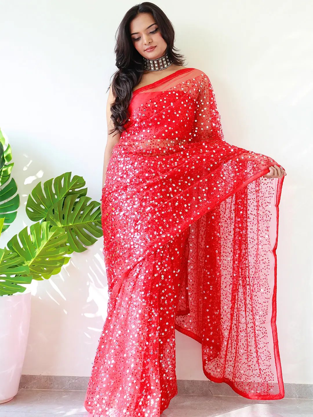 Model showcasing red net saree with intricate sequins work.