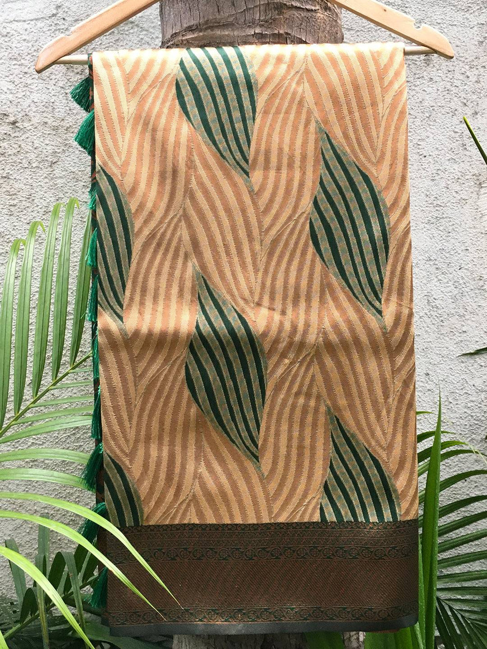 Close-up of brown Tussar silk Ikkat saree with green leaf patterns.