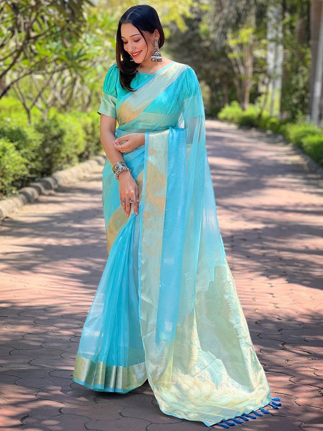 Model in turquoise organza saree, showcasing gold zari border