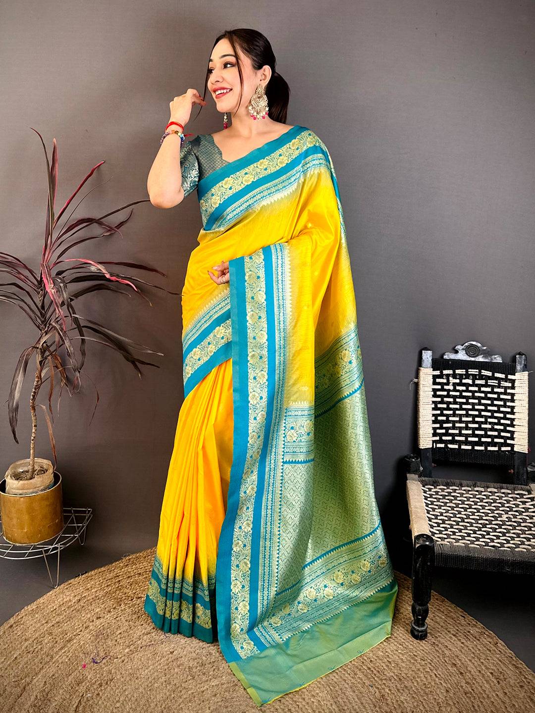 Woman in yellow and blue silk saree with gold zari border, styled with earrings and bangles, traditional festive look