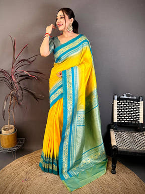 Woman in yellow and blue silk saree with gold zari border, styled with earrings and bangles, traditional festive look