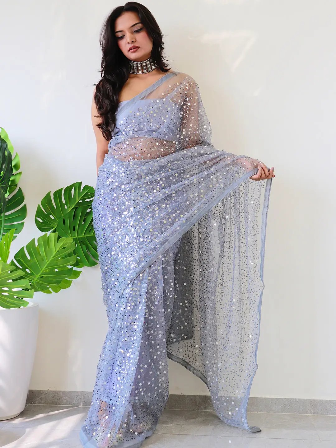 Model showcasing a net saree with shimmering sequins embroidery.