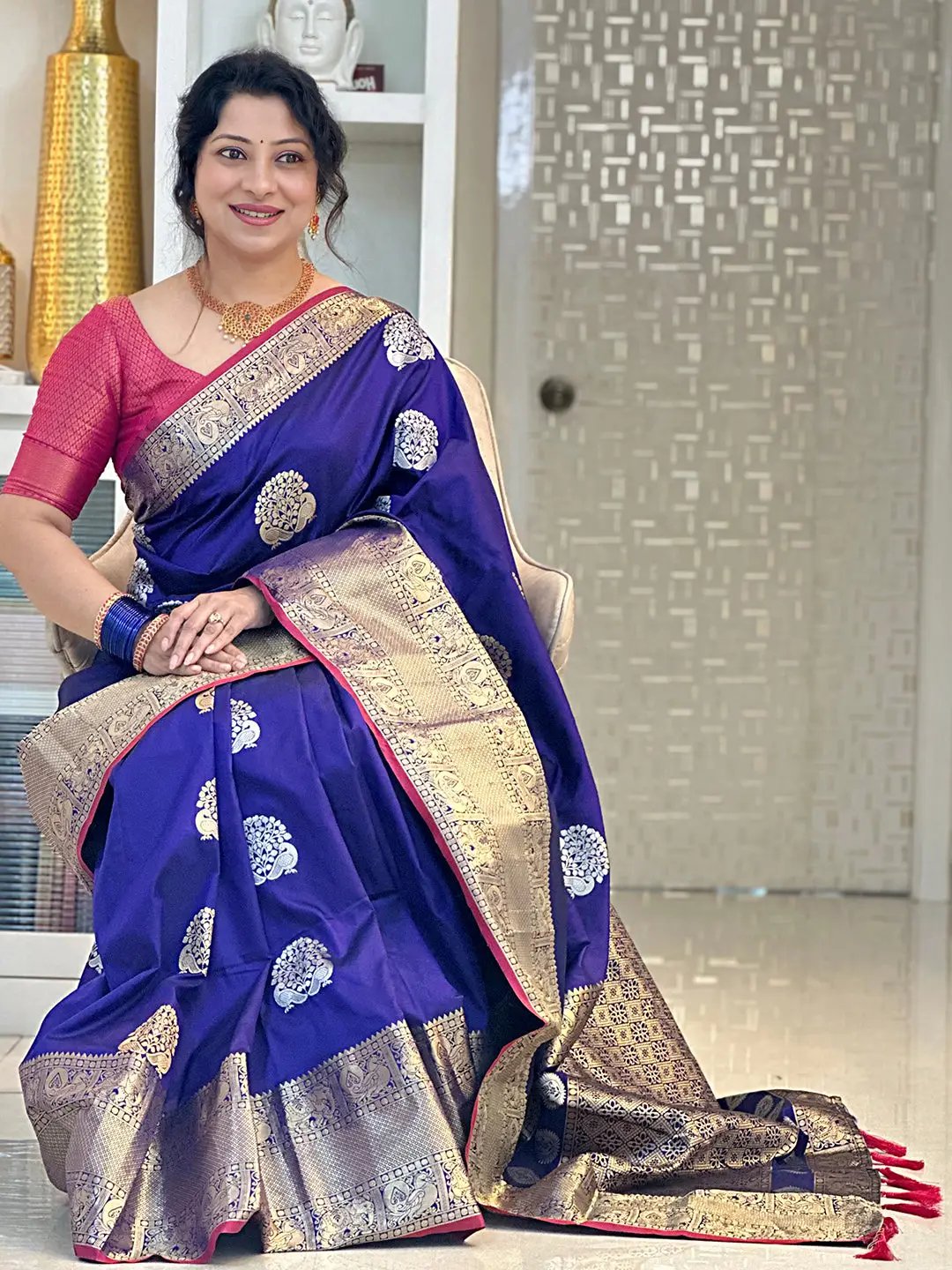 Seated woman in luxurious purple Banarasi saree with zari border.