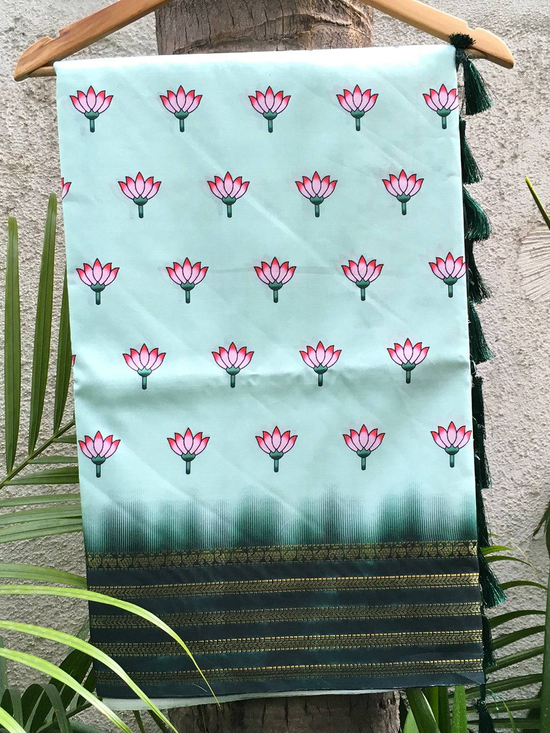 Green 2 Ton Lotus Print Silk Saree hanging on a tree