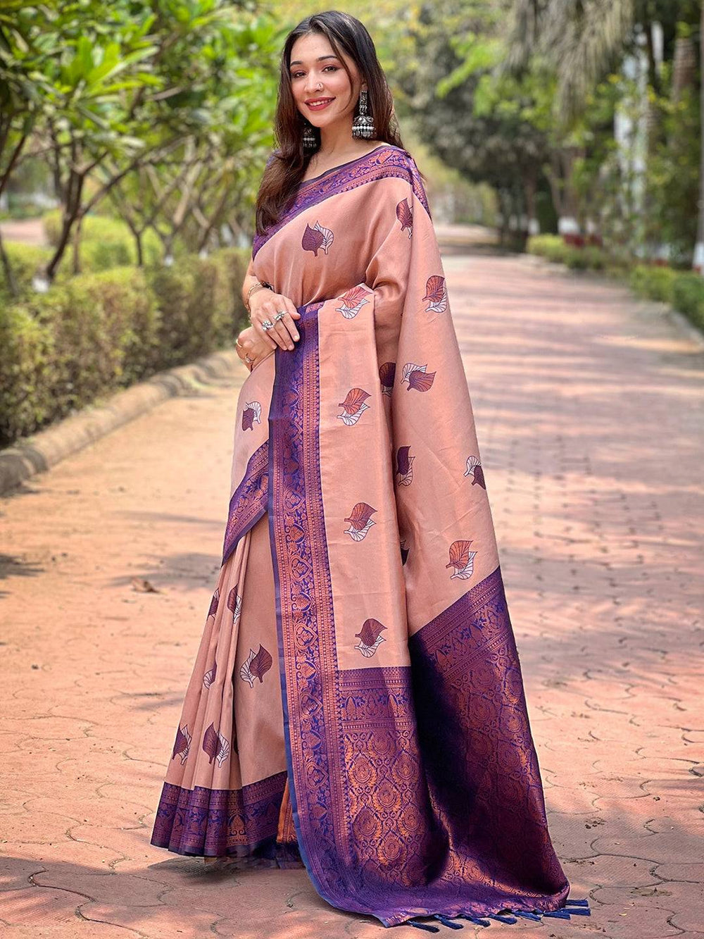 Elegant pastel peach saree with purple border, worn outdoors