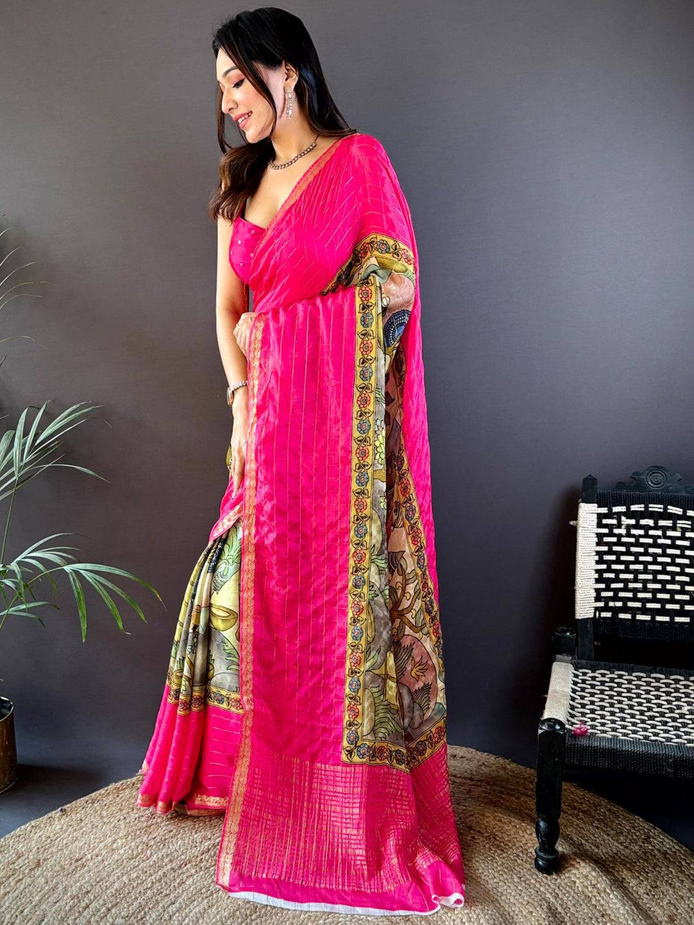 Elegant pink Kalamkari saree with artistic patterns and golden stripes