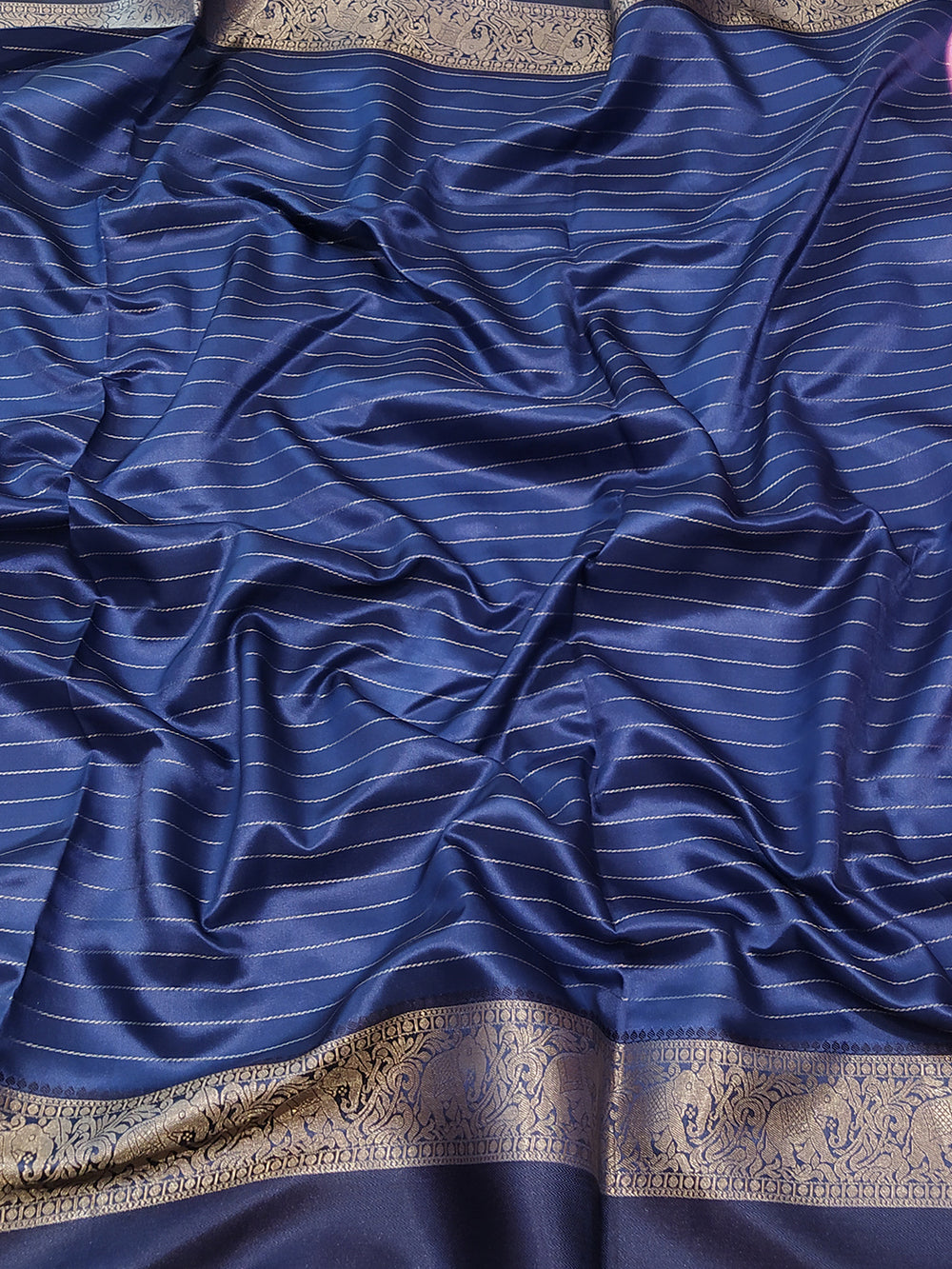 Close-up of blue silk saree fabric with gold zari stripes