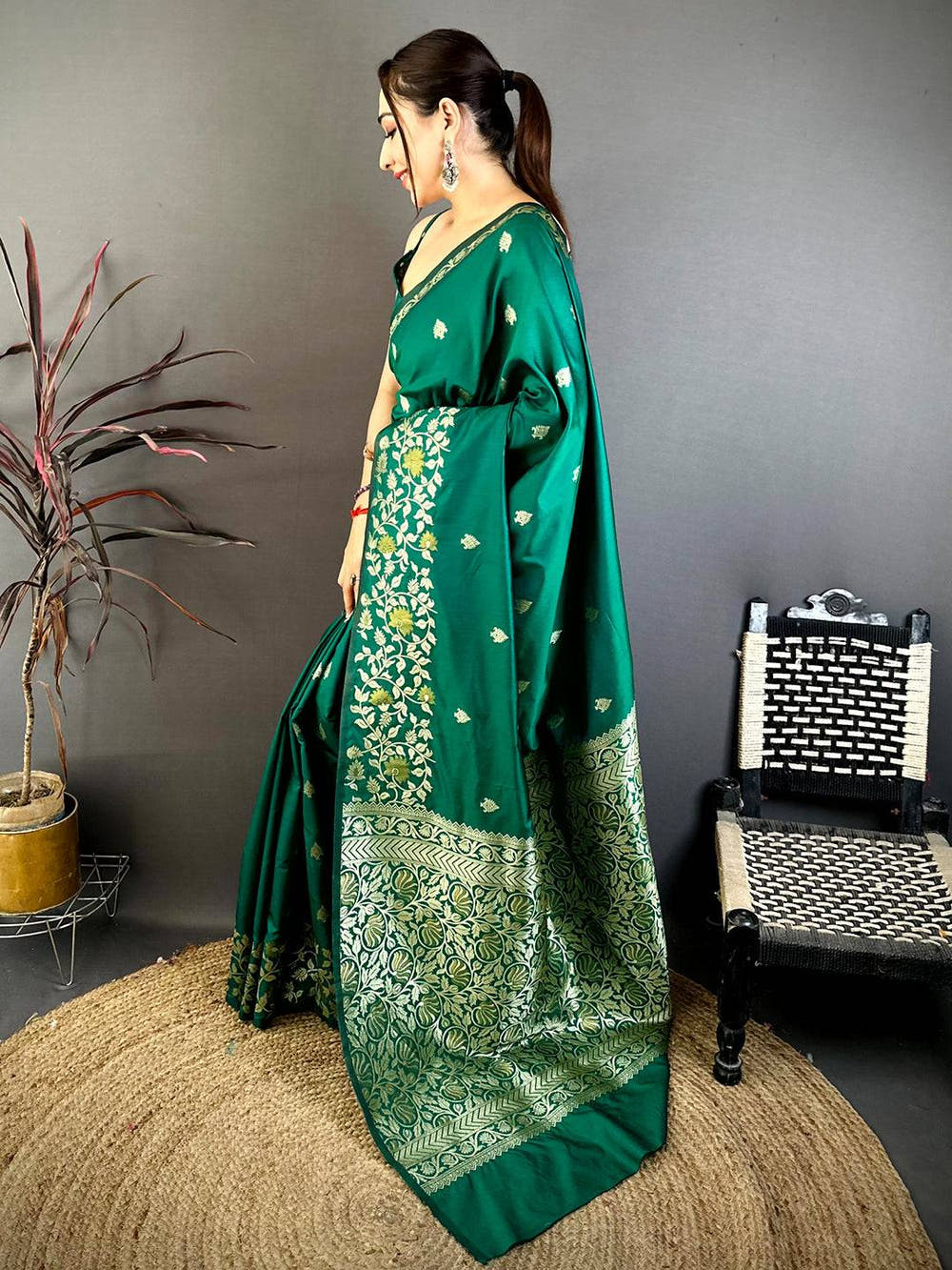 Close-up of emerald green silk saree with gold embroidery on grass